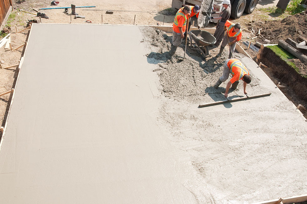 worker leveling freshly poured concrete