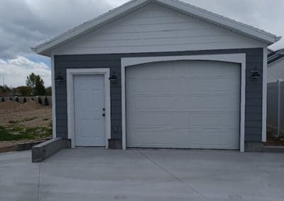 Side view of a white garage door on a gray detached garage
